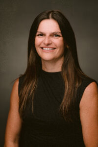 Person smiling in a professional portrait against a dark background.