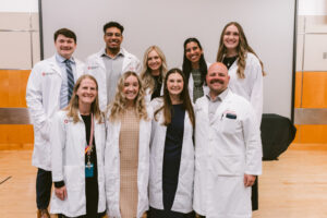 Group of people smiling in white coats.