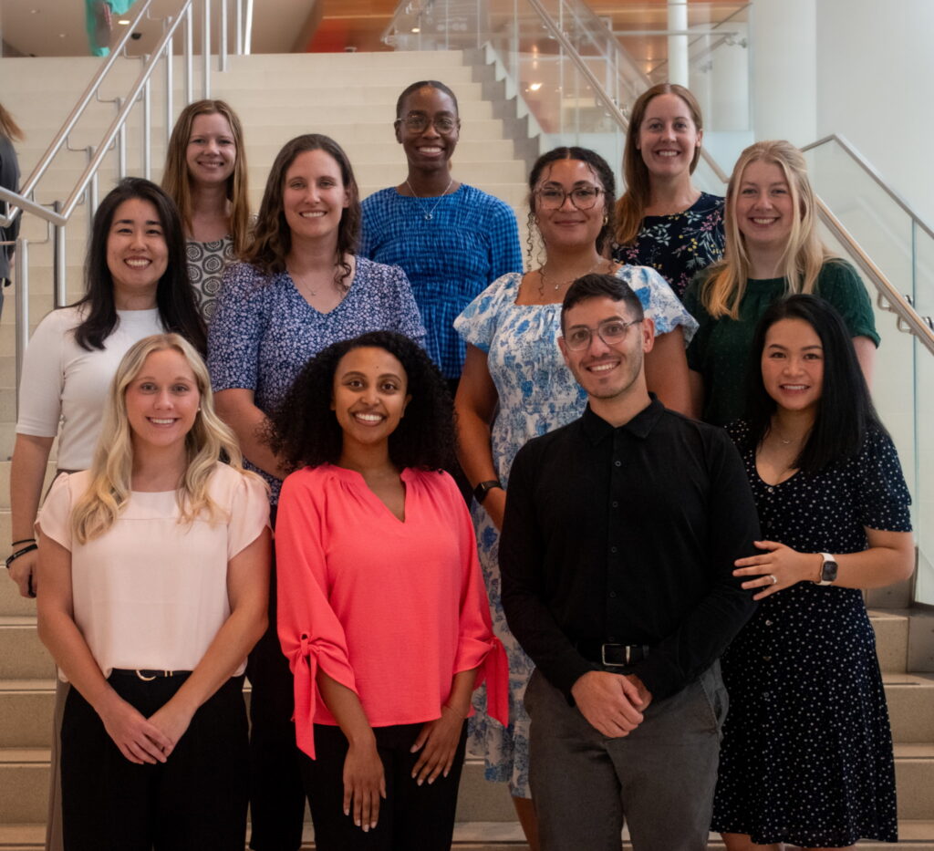 Group photo of eleven people standing on an indoor staircase in a modern building